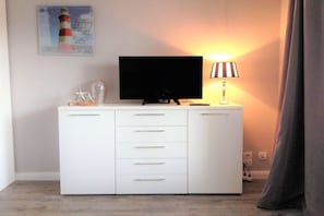 Ein weißes Schranksystem mit Fernseher und Lampe darauf.