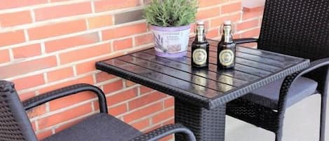A patio table with two chairs, a potted plant, and two bottles.
