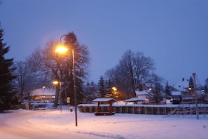 A snow-covered outdoor area with street lamps and a playground.