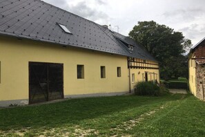 Ein gelbes Gebäude mit einem geneigten Dach, einer großen offenen Tür und einem kleinen Fenster.