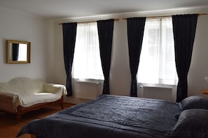 A bedroom with a bed, a chair, and a window with curtains.