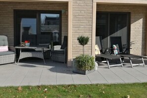 An outdoor patio with wicker furniture, a small table with a vase, and a potted plant. - Apartment in Dangast with 1 bedroom (Varel-Dangast)