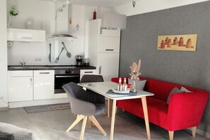 Ein gemütlicher Wohnbereich mit Küchenzeile, Esstisch und einem roten Sofa.