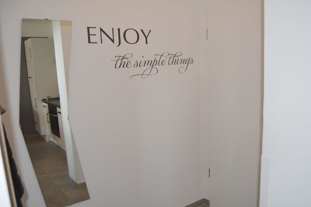 A hallway with a wall sign that reads 'ENJOY the simple things.'