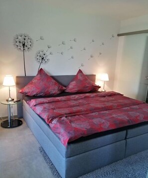 A bedroom with a bed, two bedside lamps, a wall decoration, and a door. - Apartment in Dangast with 1 bedroom (Varel-Dangast)