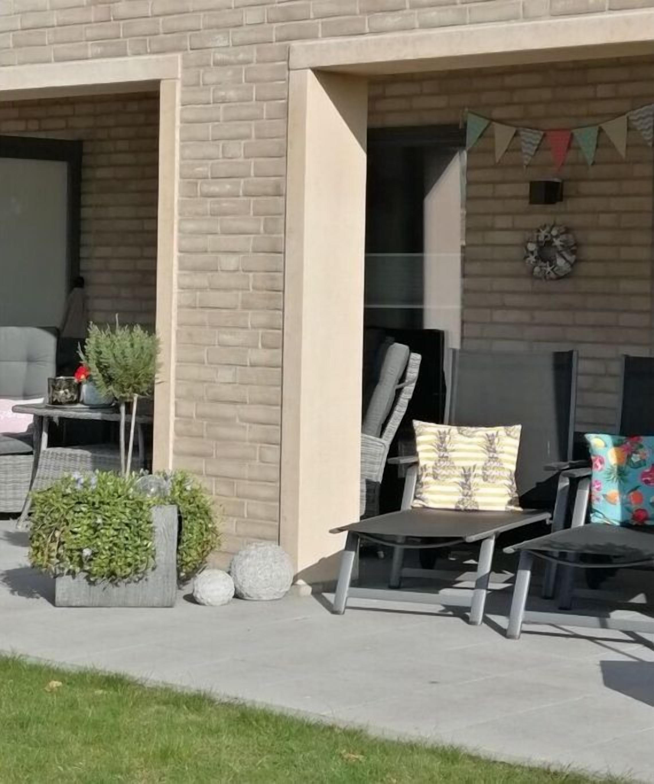 An outdoor seating area with a brick wall, a fire pit, and a small table with potted plants.