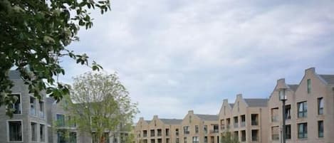 Een binnentuin met een centraal zitgedeelte, omringd door gebouwen met meerdere verdiepingen en balkons.