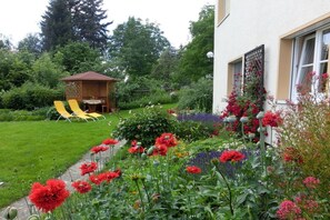 A garden with a variety of flowers and a small wooden structure. - Holiday apartment in Struppen with barbecue (Struppen)