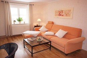 A living room with a sofa, a glass coffee table, a lamp, and a framed picture on the wall. - Holiday apartment in Struppen with barbecue (Struppen)