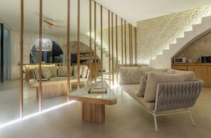 A modern living room with a sofa, coffee table, and a staircase with a stone wall. - Kona Resort Pererenan E (Badung)