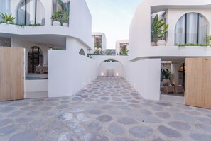 A modern building with a stone-paved courtyard, white walls, and potted plants. - Kona Resort Pererenan E (Badung)