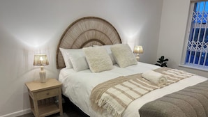 A neatly made bed with a patterned throw, a bedside lamp, and a nightstand with a drawer. - Studio 304 at The Majestic (Cape Town)