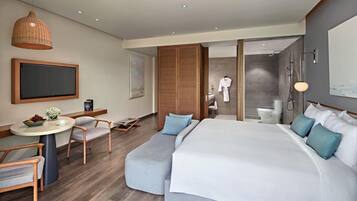 Quarto de hotel moderno com cama grande, área de estar e chuveiro.