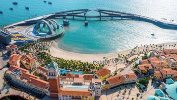 Vista aérea de uma cidade costeira com uma igreja imponente, uma ponte e uma área de praia.