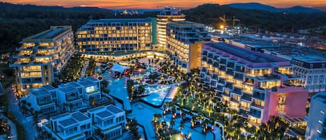 Un hotel de varios pisos con zona de piscina y jardines ajardinados.