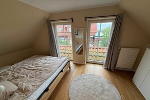 Ein Schlafzimmer mit einem Bett, einem runden Teppich und einem Fenster mit Vorhängen.