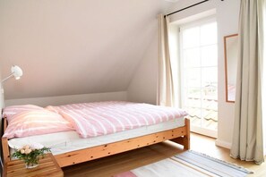 Un lit simple avec un cadre en bois, une lampe de chevet et une fenêtre avec des rideaux.