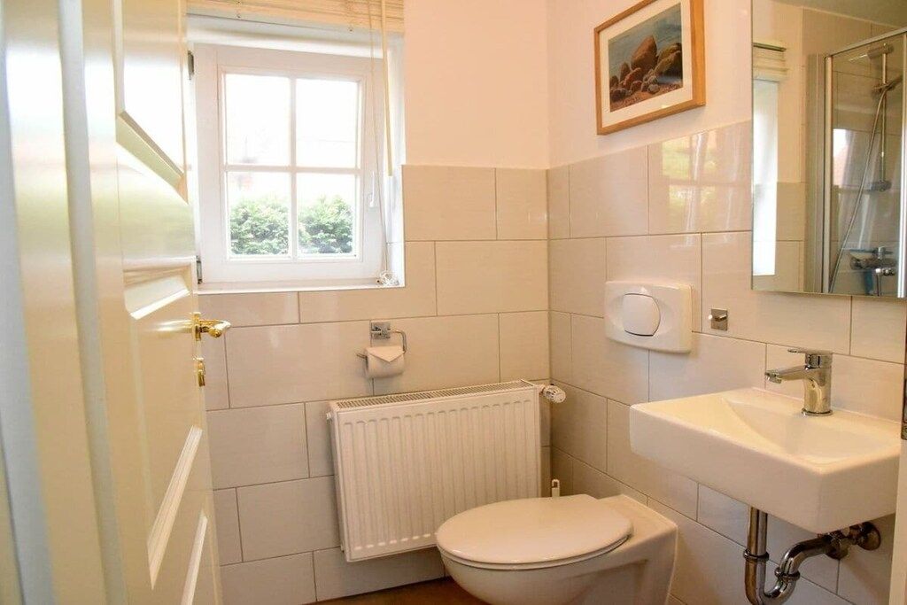Une salle de bain équipée de toilettes, d’un lavabo, d’une fenêtre et d’un radiateur.