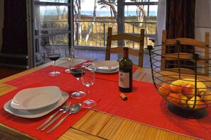 A dining table set with plates, cutlery, wine glasses, a bottle of wine, and a fruit bowl. - Juliusruh dune residence - Seewind (Juliusruh)