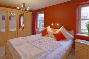 Een slaapkamer met een bed, nachtkastje, kast en raam.