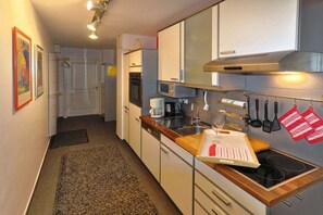 A compact kitchen with a microwave, oven, and a wooden countertop. - Juliusruh dune residence - Seewind (Juliusruh)