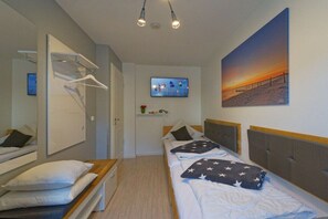 A hotel room with a bed, a TV, a painting, and a wardrobe. - Juliusruh dune residence - Seewind (Juliusruh)