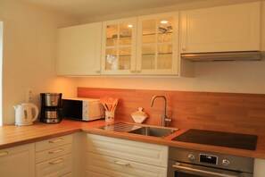 A kitchen with white cabinets, a stainless steel sink, a microwave, a coffee maker, and a toaster. - Holiday home with 4 bedrooms (Timmendorfer Strand)