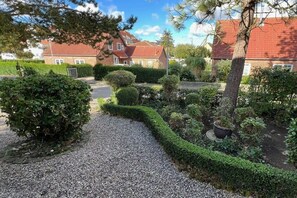 A gravel pathway leading to a residential area with neatly trimmed hedges and a variety of plants. - Holiday apartment with 2 bedrooms (Fehmarn)