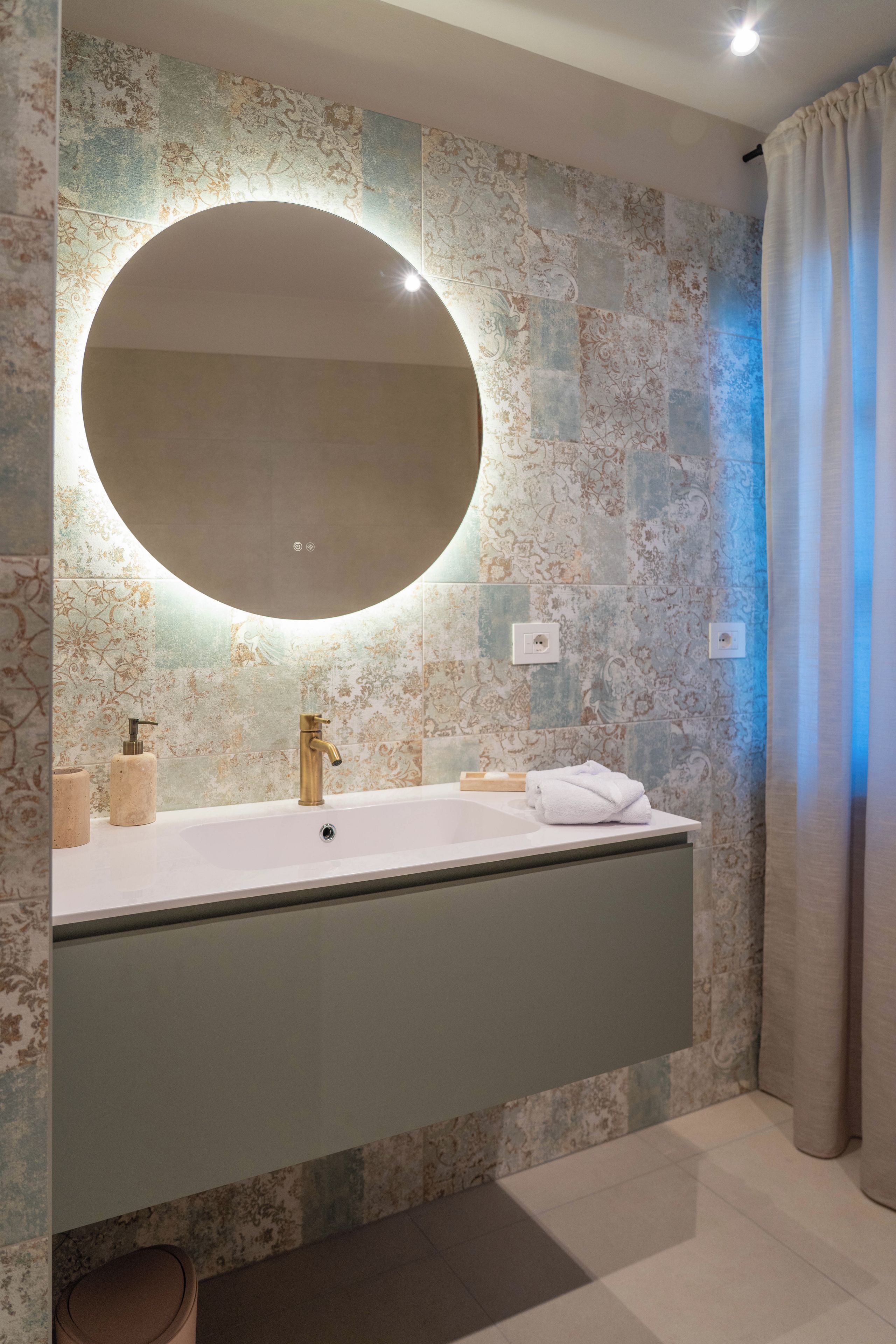 A bathroom with a large mirror, a sink, and a towel rack.