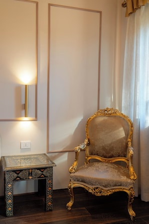 Una stanza con un grande specchio, una sedia decorativa e un tavolino con decorazioni elaborate.