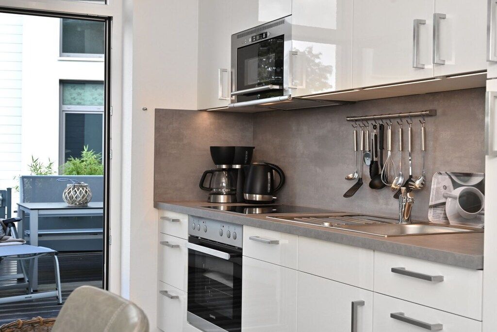 A modern kitchen with stainless steel appliances, a built-in oven, and a coffee maker.