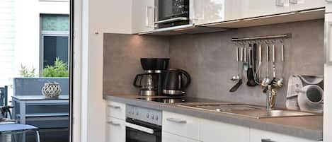 A modern kitchen with stainless steel appliances, a built-in oven, and a coffee maker.