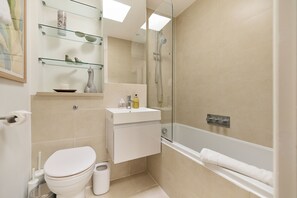 A modern bathroom with a toilet, sink, and shower. - The Two-Bedroom Edit (London)