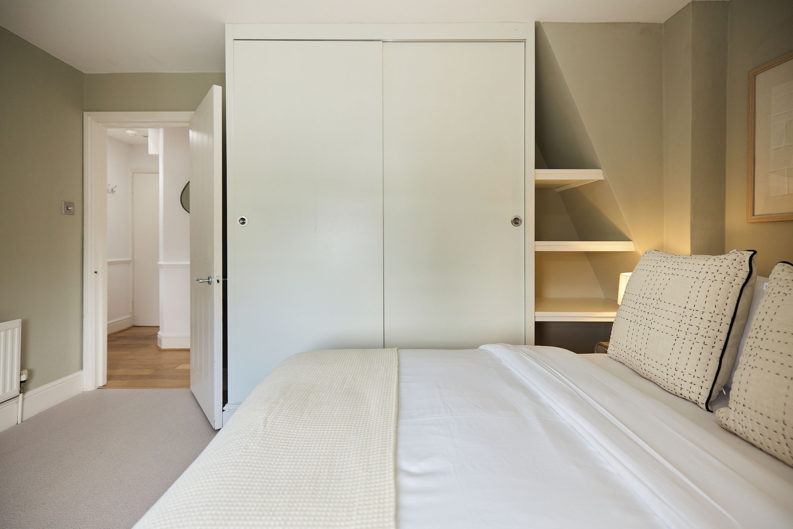 Une chambre à coucher avec un grand lit, une armoire et une étagère.
