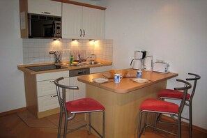A compact kitchen with a microwave, sink, and coffee maker. There are three stools and a small island with a sink. - 13 Heringsdorf Lake Castle (Heringsdorf)