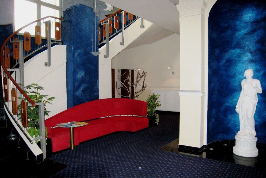 A lobby with a red sofa, a staircase, and a white statue.
