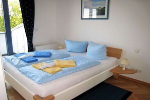 Ein Hotelzimmer mit Bett, Nachttisch, Lampe und einem Fenster mit Vorhängen.