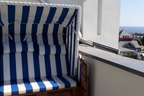 A balcony with a striped blue and white canopy, a wooden chair, and a view of buildings and the sea. - 13 Heringsdorf Lake Castle (Heringsdorf)