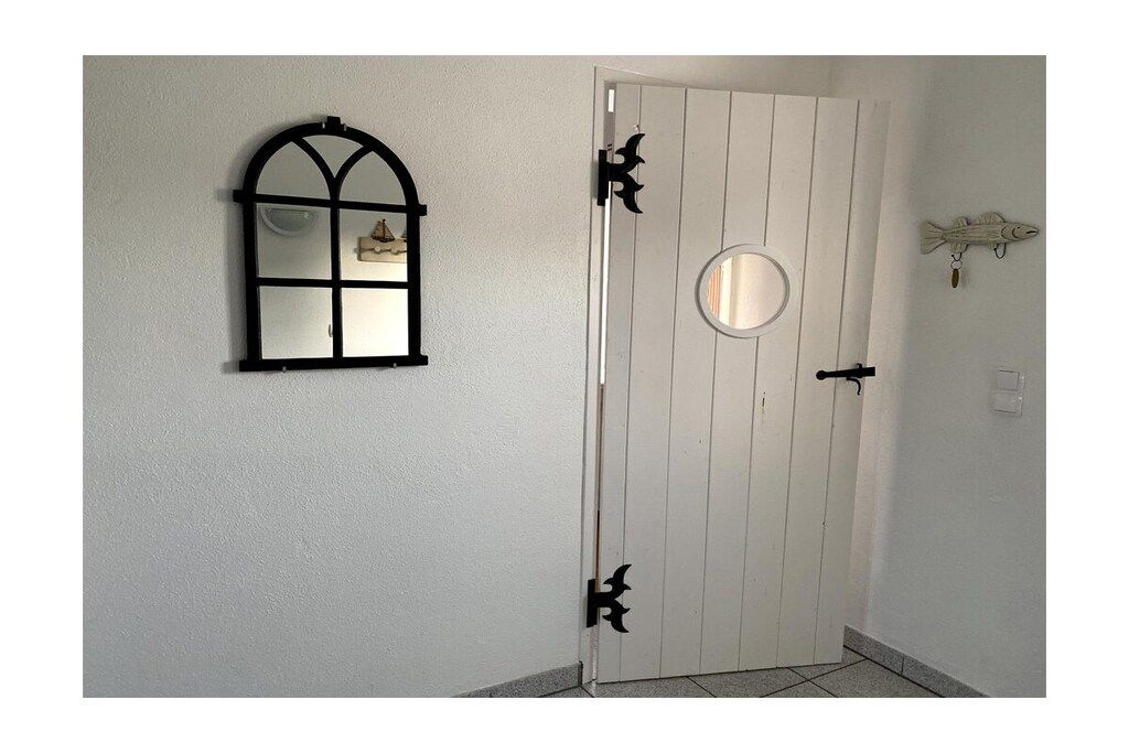 A white door with a round mirror and a black-framed window.