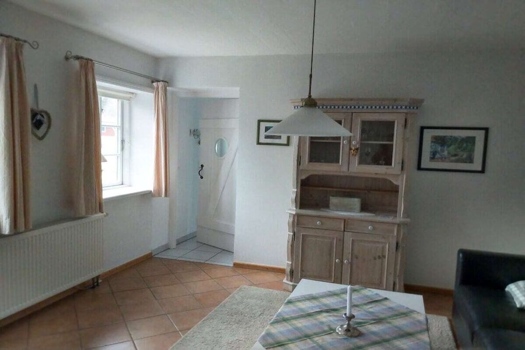 A room with a radiator, a window with curtains, a cabinet, and a table with a placemat.