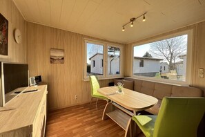 A modern kitchen with a wooden countertop, a built-in oven, and a window overlooking a residential area. - Bungalow holiday paradise (Koserow)