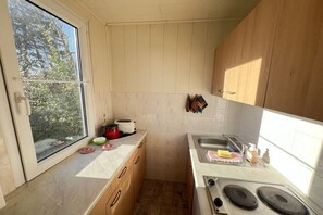 A compact kitchen with a window, a stove, and a sink. - Bungalow holiday paradise (Koserow)