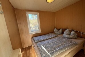 A bedroom with a single bed, a window, and a wooden ceiling. - Bungalow holiday paradise (Koserow)