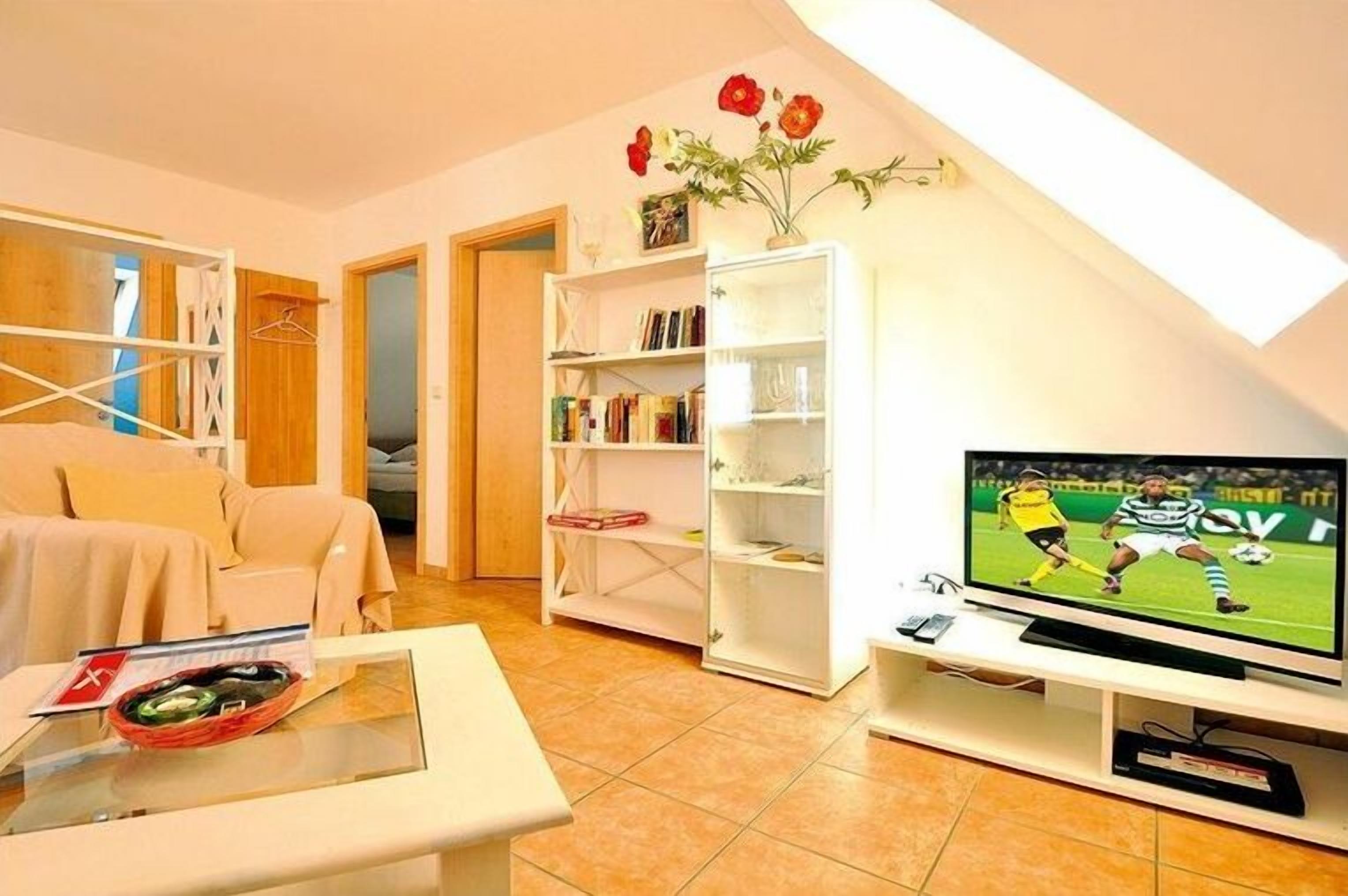 Un salon avec un canapé, une table basse, un téléviseur et une bibliothèque.