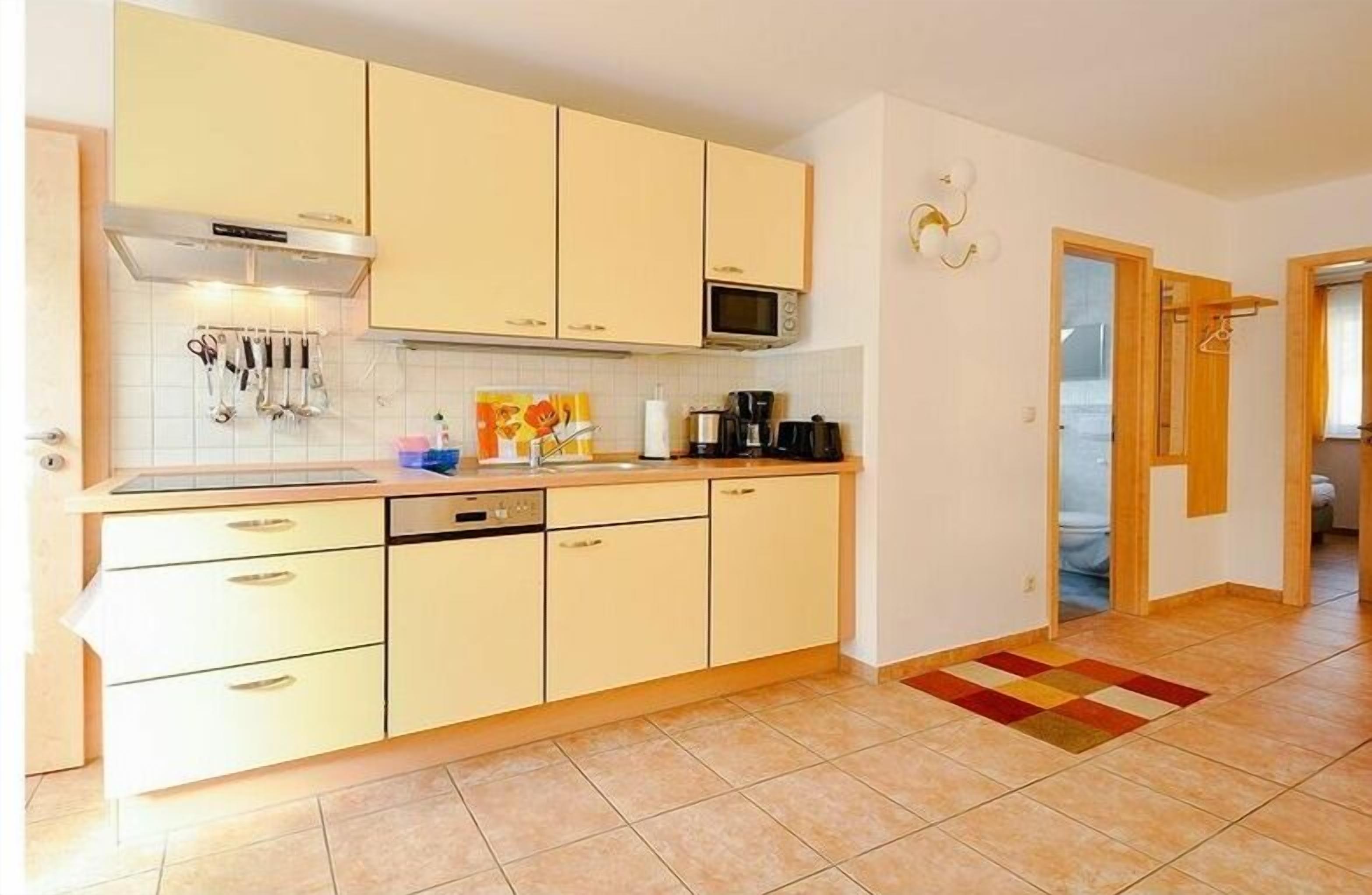 A compact kitchen with a microwave, stove, and various utensils.