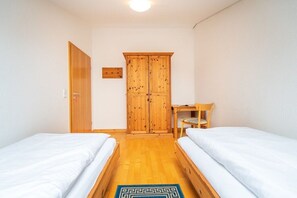 Ein Schlafzimmer mit zwei Betten, einem Holzschrank, einem Schreibtisch und einem Stuhl.
