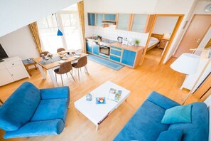 Ein kompakter Wohnbereich mit Küchenzeile, Essbereich und einer Sitzecke mit Sofas.