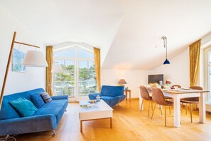 A modern living room with a sofa, coffee table, dining table, and chairs. - Holiday apartment with 2 bedrooms (Juliusruh)