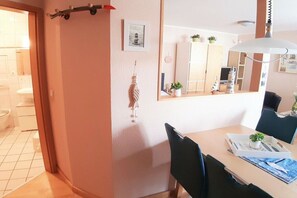 Ein Zimmer mit Esstisch, Stühlen, einem Spiegel und einer kleinen Topfpflanze auf dem Tisch.