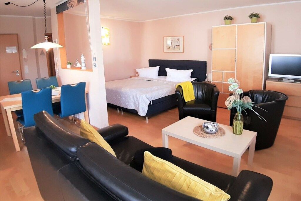 Une chambre d’hôtel comprenant un lit, un canapé, une table à manger avec des chaises, un téléviseur et un meuble.
